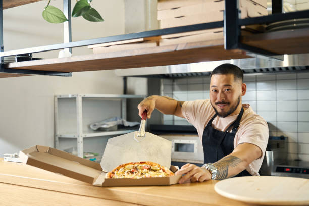 istock Contented cook packing up fresh pizza for takeaway 1420573055
