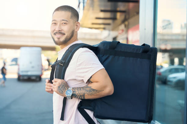 istock Joyful food delivery guy smiling while doing his job 1420573162
