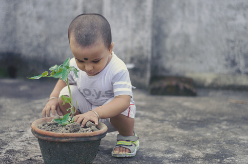 Cute Little baby boy with Flower tub loves to play in the dirt.