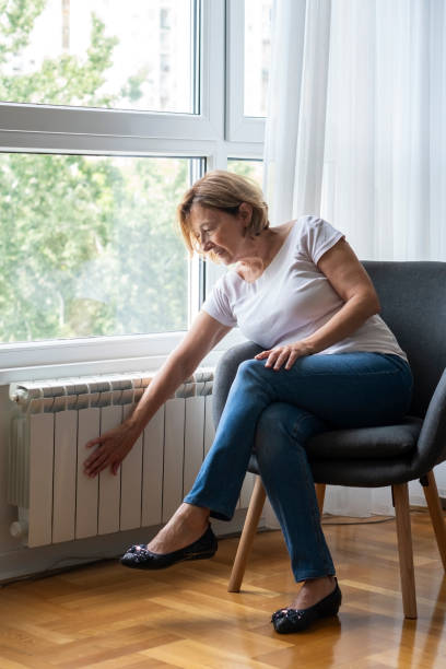 istock Senior woman touching cold home radiator 1420579796