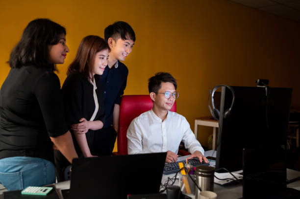 istock Group of Asian business colleagues having meeting and discussing office work using a desktop computer at the workplace during night hours. 1420580144