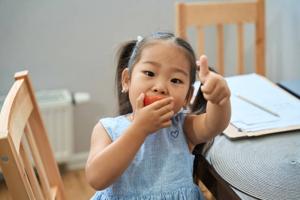 istock Little girl eats an apple and shows ok 1420585913