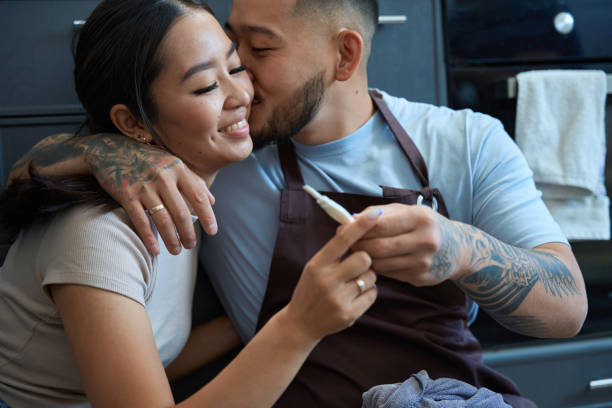 Man kissing his beloved wife on the cheek Man kisses his beloved wife on the cheek, they rejoice at a positive pregnancy test men close up 20s asian ethnicity stock pictures, royalty-free photos & images