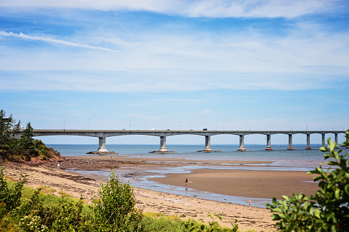 Cape Jourimain - August 22, 2022. View of the Confederation Bridge with people walking on the foreground beach.