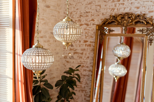 Interior in oriental style with vintage golden mirror and crystal chandelier on a brick wall background