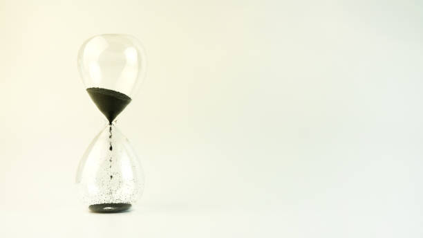 istock Hourglass on a white background. Black sand flows down the transparent glass. copy space. 1420593514