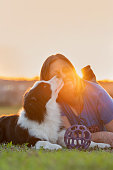 istock Woman and Border Collie dog licking her face lying on the grass 1420603612