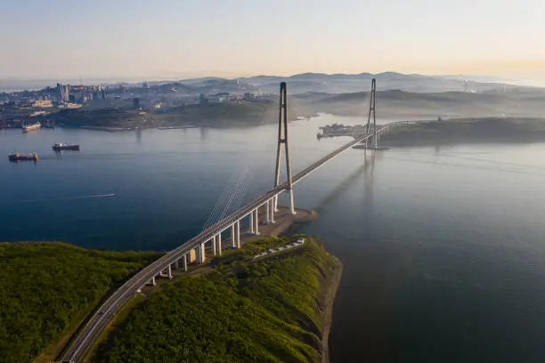 Aerial view of the Russian bridge from the mainland to the Russian island in the East Sea. The longest longest span. Summer dawn on the sea. Guys in the colors of the Russian flag. Vladivostok, Russia