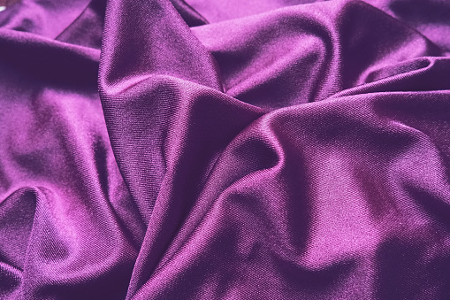 Velour fabric, similar to silk. Textiles in a folds and beautiful waves. Purple, pink, magenta shades on the drapery. Sewing material for evening dresses, furniture upholstery, curtains and interior.