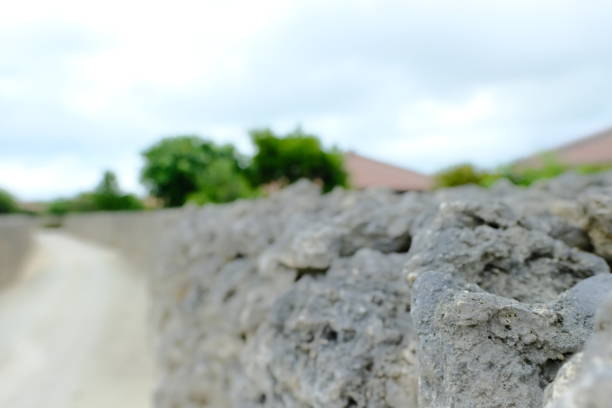 Close-up view of an aged stone wall constructed from smooth, round rocks, with a blurred golden field in the background, showcasing a rustic and natural countryside scene in soft tones.