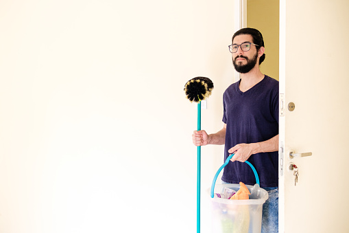 Portrait of latin man cleaning empty apartment.