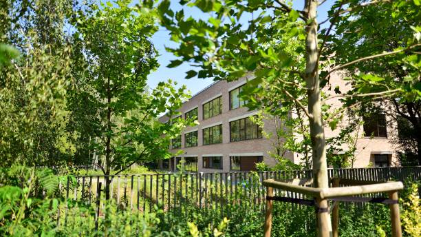 istock Modern office building stands among lush green trees. 1420654390