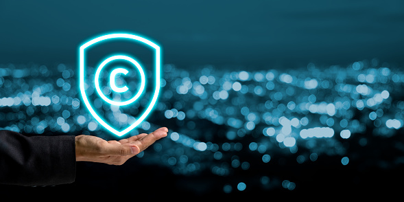 Copyright or patent concept, Business person hand holding VR screen copyright icon with blue bokeh background, Copyleft trademark license, Creation ownership against piracy crime.