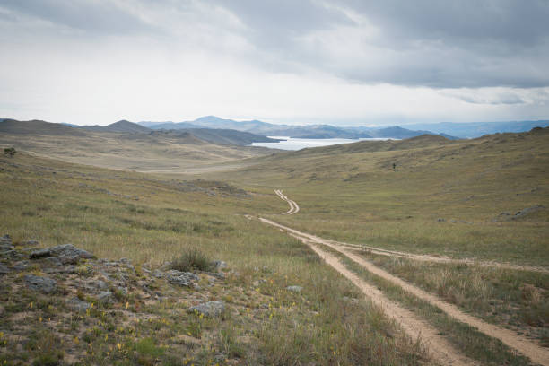 Dirt road through a beautiful valley on Olkhon island at Baikal Dirt road through a beautiful valley on Olkhon island at Baikal. High quality photo siberia summer stock pictures, royalty-free photos & images