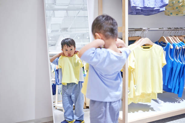 Cheerful young Caucasian boy selecting eyewear, colorful glasses array, inviting atmosphere in eyecare center.
