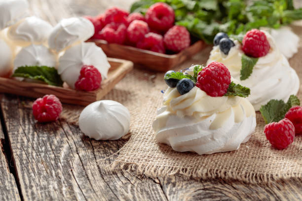 Dessert Pavlova with raspberries, blueberries and mint on a old wooden table.