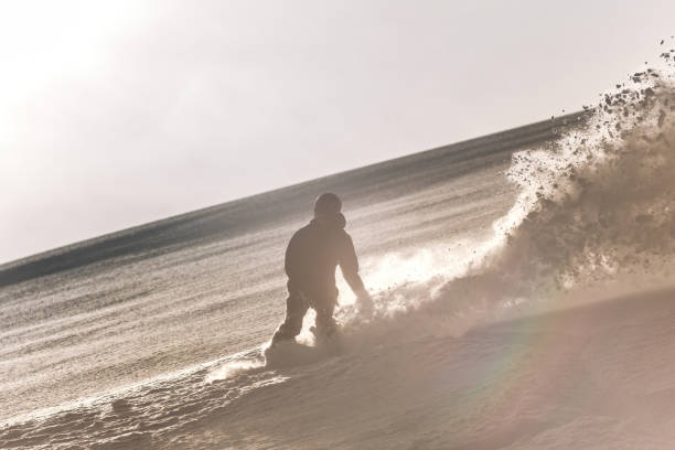 um homem snowboarder em curvas de velocidade e freios, espirrando neve profunda solta - freeride - fotografias e filmes do acervo