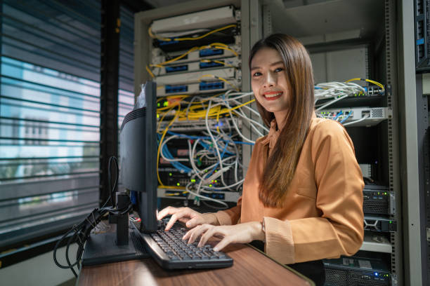 istock A female programmer is working in a server room. The girl is standing next to the computer racks of the data center. The administrator looks at the monitor with network settings. 1420662782