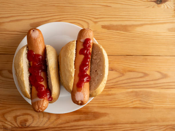 istock Boiled sausage with a bun on a wooden background. 1420665410