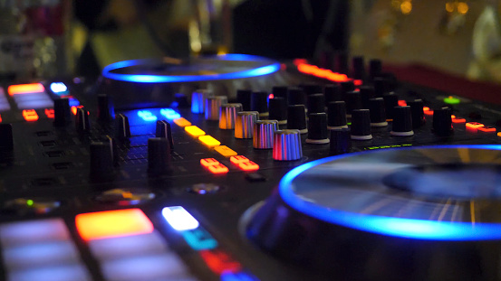 Close up of dj playing party music on modern cd usb player in disco club - Nightlife and entertainment concept. DJ turntable console mixer controlling with two hand in concert nightclub stage 4K