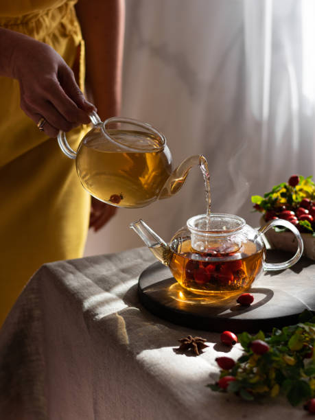 istock female hand pours hot herbal tea into a glass mug. Vertical 1420678228