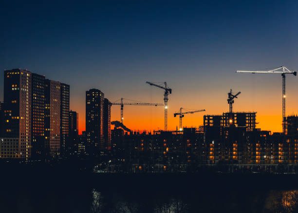 Skyline with tower cranes Metropolitan skyline with tower cranes building high-rise residential buildings in evening time. Steel frame structure in sunlight. Industrial background. Lifestyle civil engineering stock pictures, royalty-free photos & images