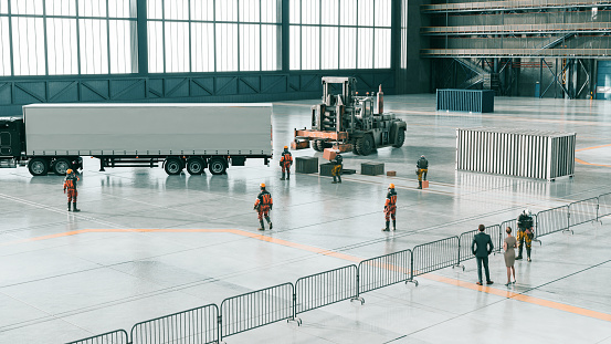 Workers with helmets are ready to move cargo into a big truck. They stand inside a large factory or warehouse. Concept of supply chain movement. Digitally generated image.