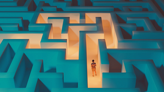 Woman stands in the middle of dark maze. Lights guide the way for her. Concept of standing in front of a challenge and finding the right solution to move on.