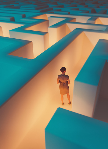 Woman stands in the middle of dark maze. Lights guide the way for her. Concept of standing in front of a challenge and finding the right solution to move on.