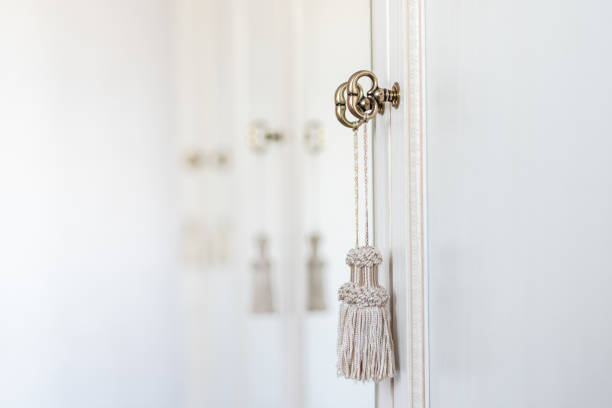 istock Bronze keys in the cabinet door with decorative tassels. Selective focus. Copy space. White background. 1420683074