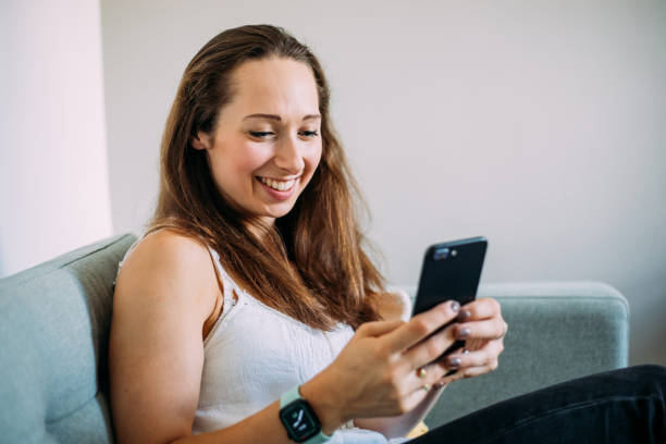 istock Cheerful Woman Using Mobile Phone at Home 1420683485