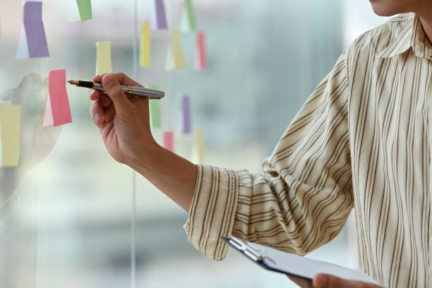 istock Cropped view portrait of a man taking note on a sticky note while holding a note pad. For business and finance concept. 1420683583