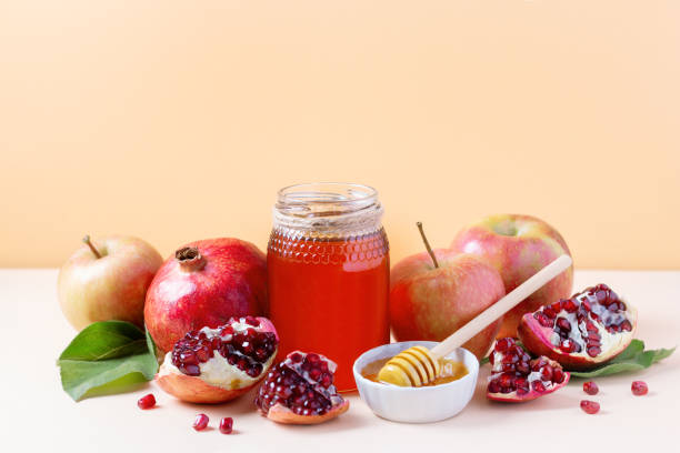 Apples, jar of honey and pomegranates on tray for Jewish holiday Rosh Hashanah Apples, jar of honey and pomegranates on tray for Jewish holiday Rosh Hashanah on neutral background, copy space rosh hashanah stock pictures, royalty-free photos & images