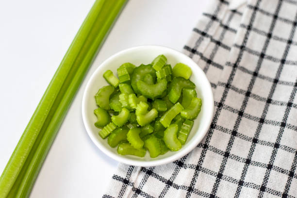 istock Celery slices in a small white bowl on a white plate with a napkin. Top view 1420686161