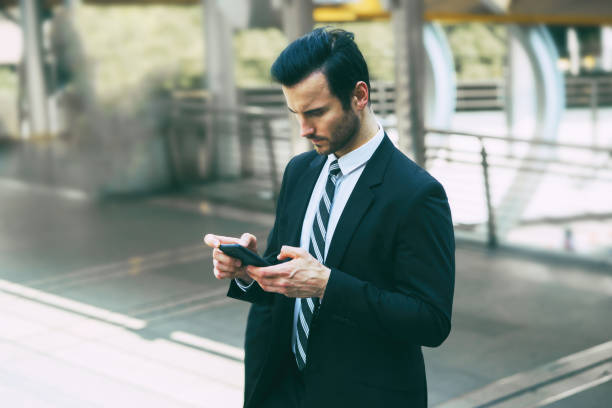 istock A handsome young businessman standing outdoors and looking at smartphone,using mobile phone control the business in daily life,internet of things IOT ,Business concept. 1420687452