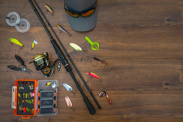 istock Spinning fishing tackle set. Spinning rod with reel, lures, baits, spoon, spinner, hooks, cap, sunglasses on wooden platform 1420688621