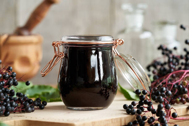 Black elder syrup with fresh elderberries stock photo