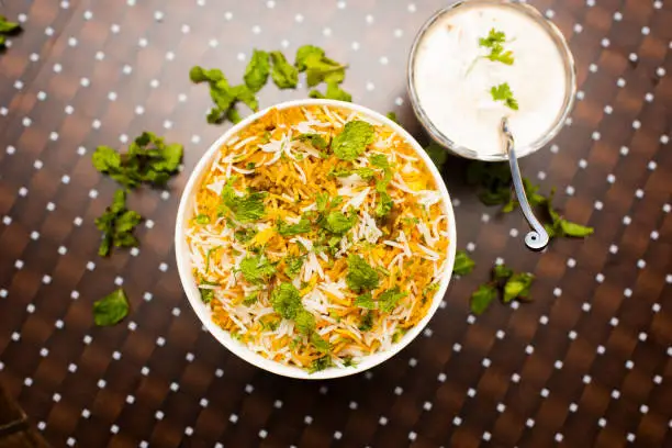 Photo of Murgh Dum Biryani or chiicken Dum Biriyani with raita served in a dish isolated on table background top view of bangladesh food