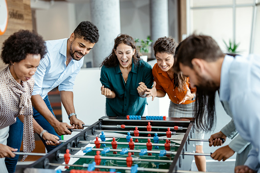 Colleagues playing table football in modern office