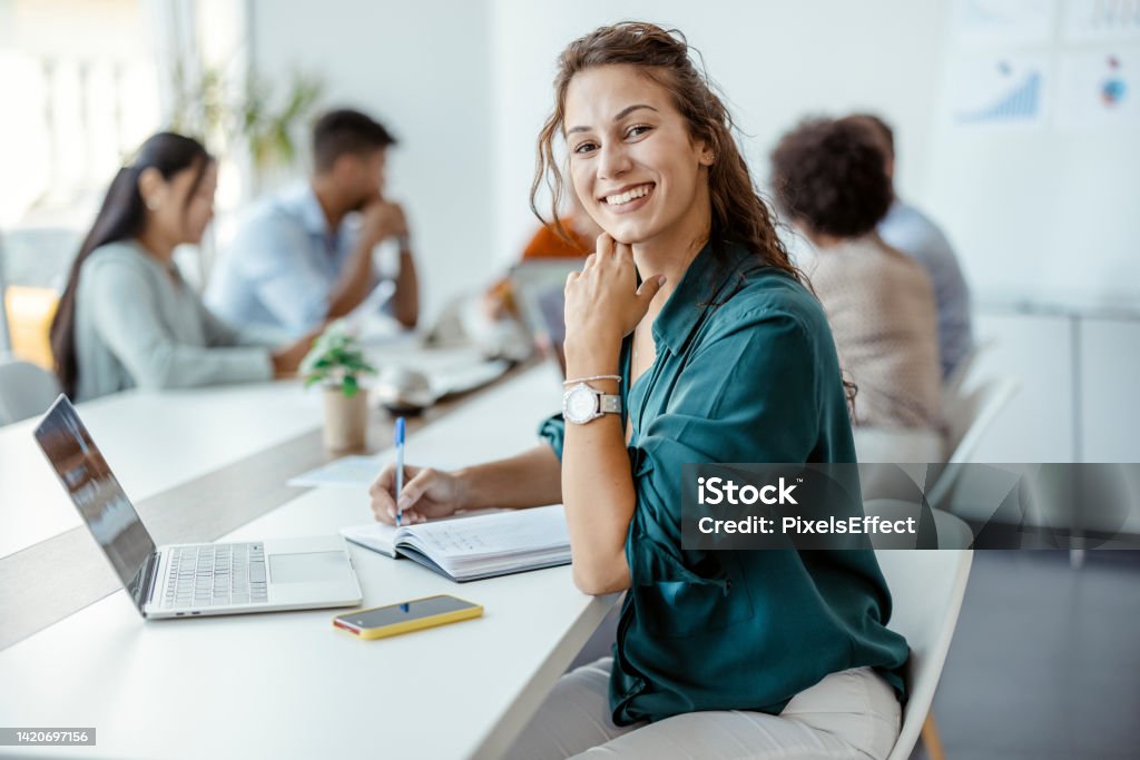 Leadership, Manager and Team Leader Female Employee Smiling in the Office, With Her Colleagues in Background. Shallow Focus Office Stock Photo