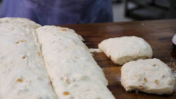 gros plan pour le boulanger coupant la pâte en morceaux avant de la cuire et de les peser à la boulangerie. images d’archives. femme faisant des morceaux de pain à partir de pâtisserie crue une mise sur la balance. - food and drink healthy eating expertise professional occupation photos et images de collection