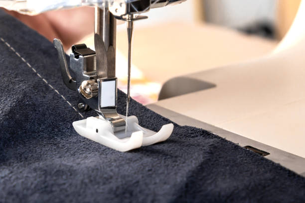 istock Sewing machine foot with a needle sews fabric. Close-up. Place for text 1420705234