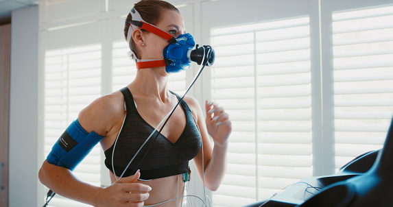 Vo2 max training mask with a young athlete exercising for fitness during a workout at the physio to monitor her health and wellness. Cardio, endurance and running for medical testing and insurance