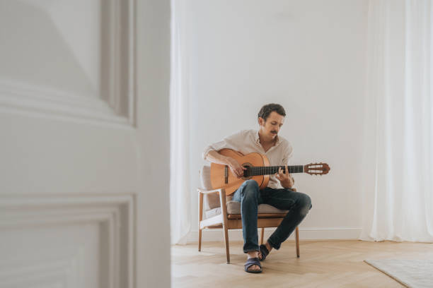 istock Man playing guitar in the living room 1420711683