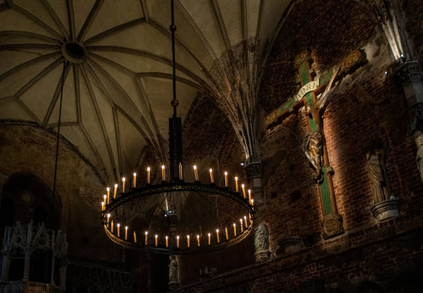 Ancient gothic catholic church interior. Burning candles and ruined religious sculptures
