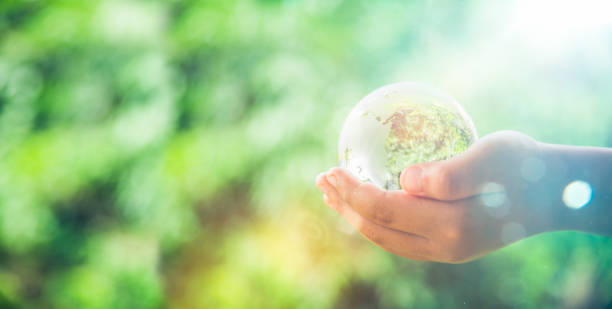 istock Human hands holding earth sphere crystal or sustainable globe glass with sunlight at green nature background in ecology environment forest. concept of conservation environmental, protection planet. 1420716033