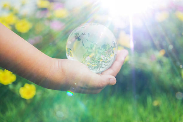 istock Human hands holding earth sphere crystal or sustainable globe glass with sunlight at green nature background in ecology environment forest. concept of conservation environmental, protection planet. 1420716159