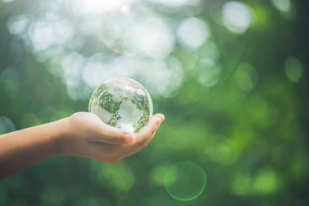 istock Human hands holding earth sphere crystal or sustainable globe glass with sunlight at green nature background in ecology environment forest. concept of conservation environmental, protection planet. 1420716378