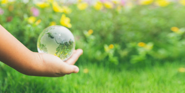 istock Human hands holding earth sphere crystal or sustainable globe glass with sunlight at green nature background in ecology environment forest. concept of conservation environmental, protection planet. 1420716418