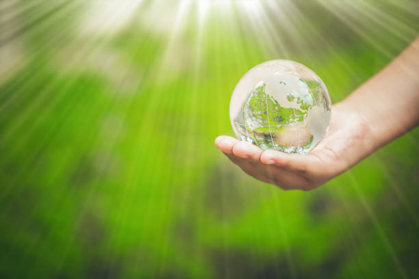 istock Human hands holding earth sphere crystal or sustainable globe glass with sunlight at green nature background in ecology environment forest. concept of conservation environmental, protection planet. 1420716496